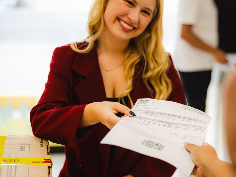 Customer handing a document over the counter at a DHL Store