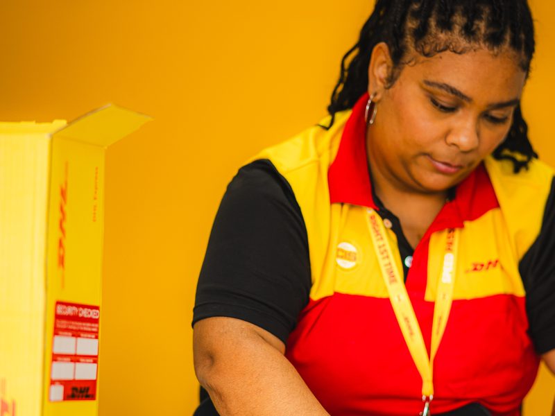 Atendente da Loja DHL embalando uma encomenda com plástico bolha