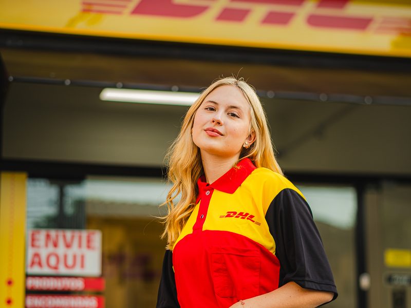 Atendente em frente à fachada de uma Loja DHL Express