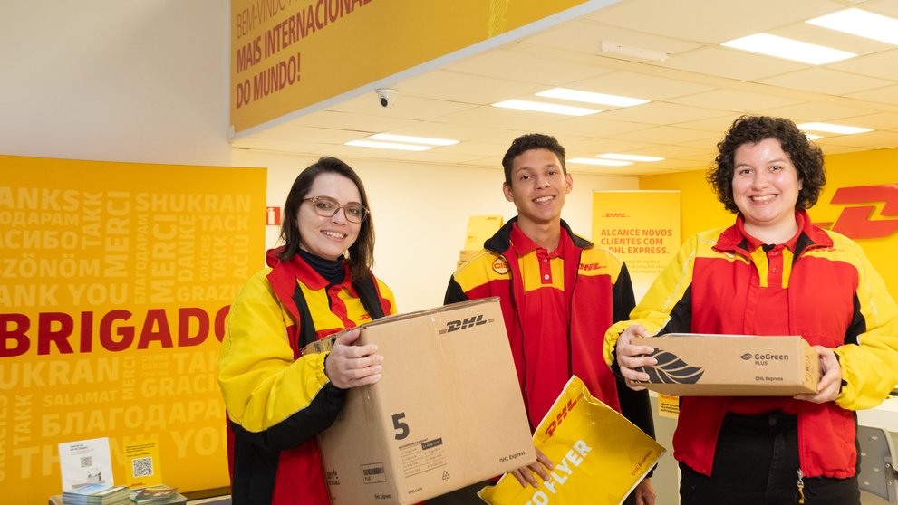 DHL Store team holding boxes and a DHL envelope at the store counter