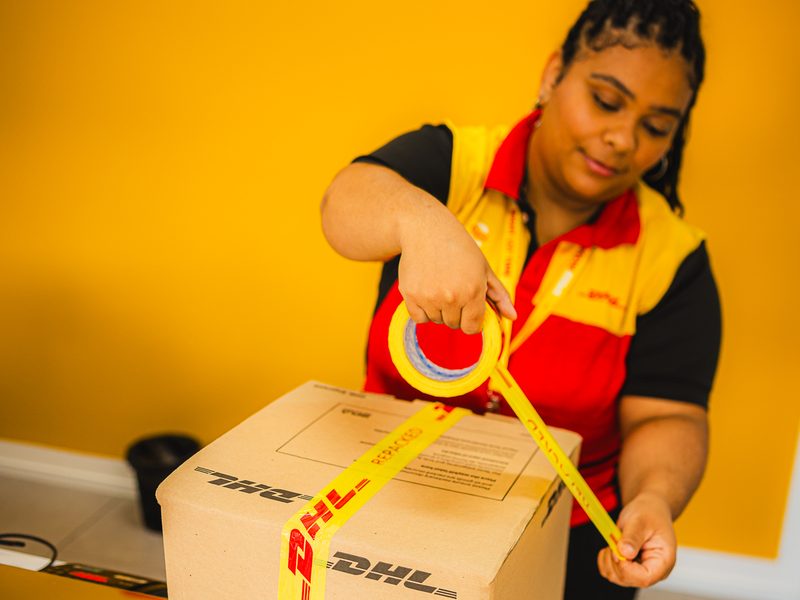 Atendente fechando a caixa com fita DHL