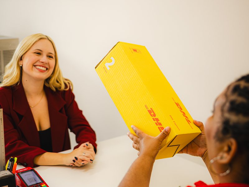 DHL Store agent receiving a DHL box from a customer