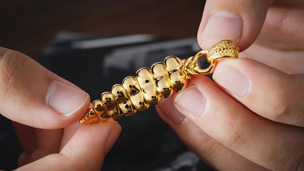 A person holding a gold chain, set for shipping jewelry overseas with care