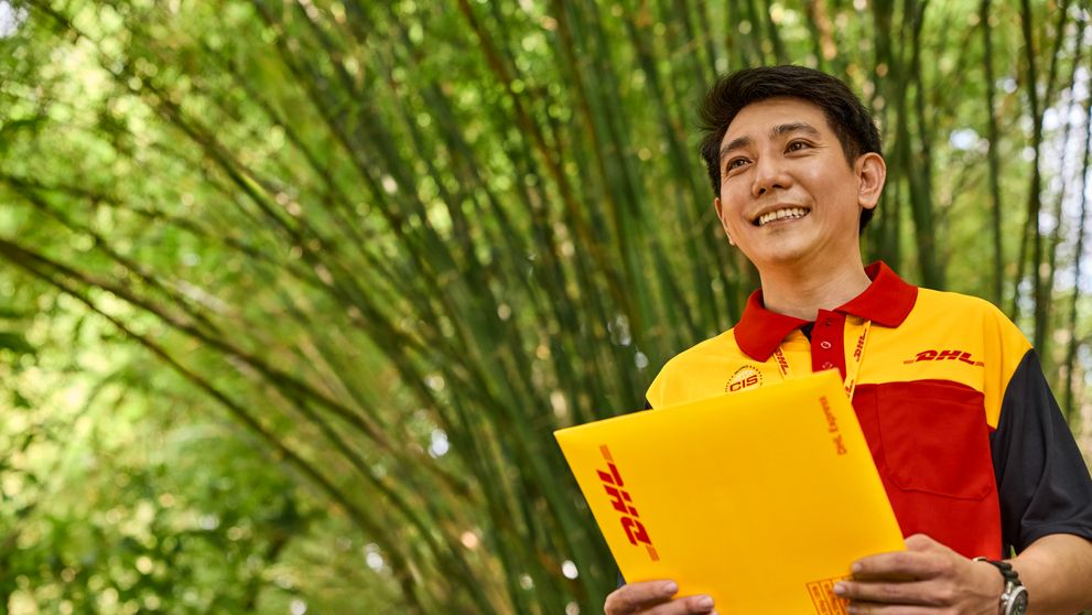 DHL Express employee holding an envelope containing key shipping documentation for customs clearance