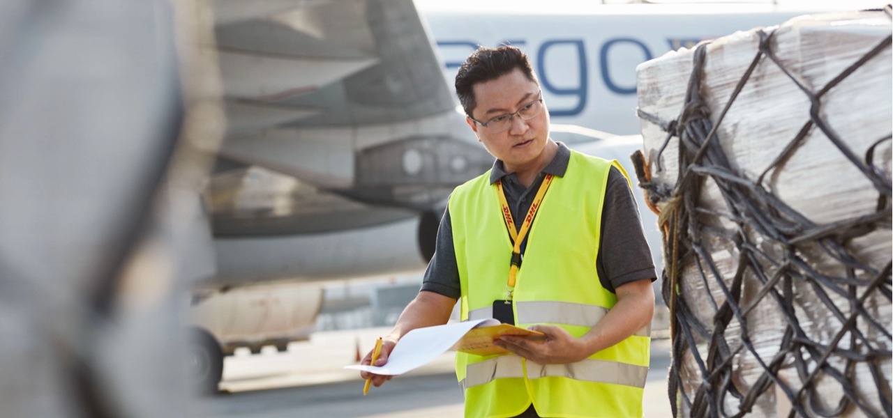 DHL 机场地勤对照单据核对航空货物。