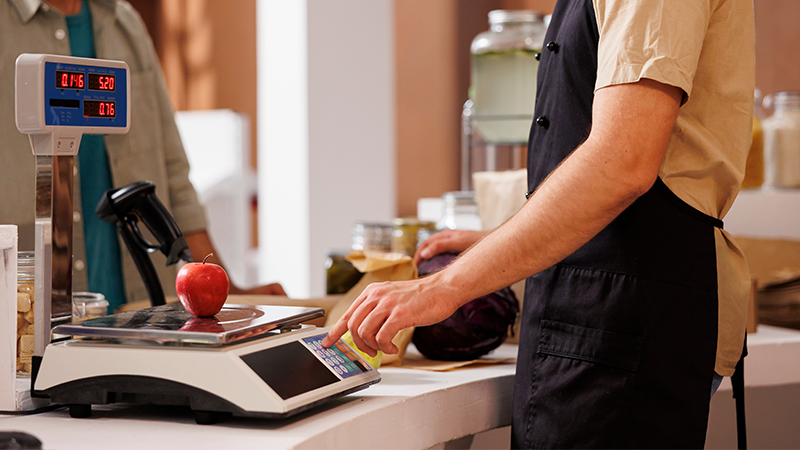 Mand der vejer æble på en vægt