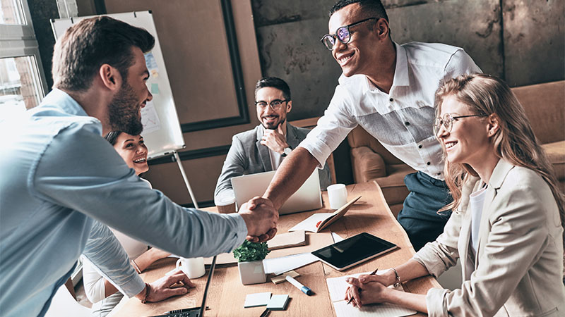 two men shaking hands over a table