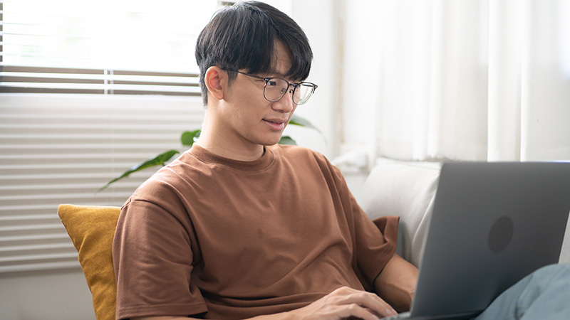 Asian man looking at laptop screen