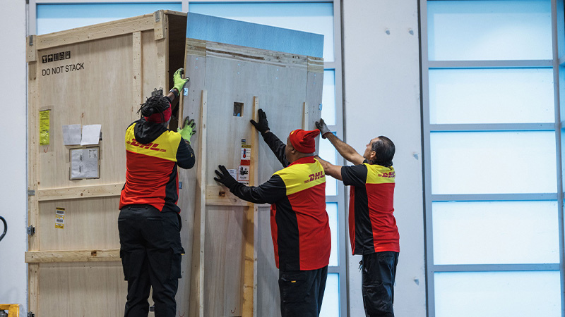 three DHL employees closing storage container