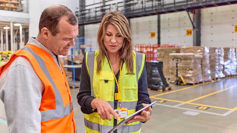 Man and woman in hi vis looking at tablet screen