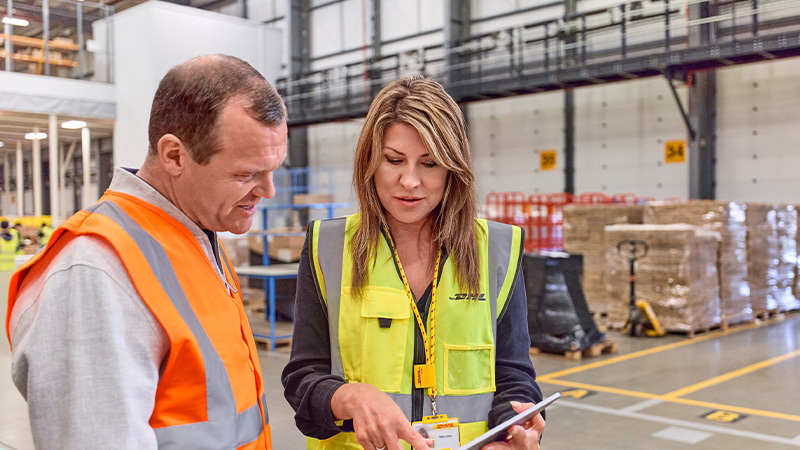 Man and woman in hi-vis suits looking at tablet screen
