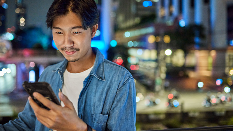 Asian man smiling at mobile phone