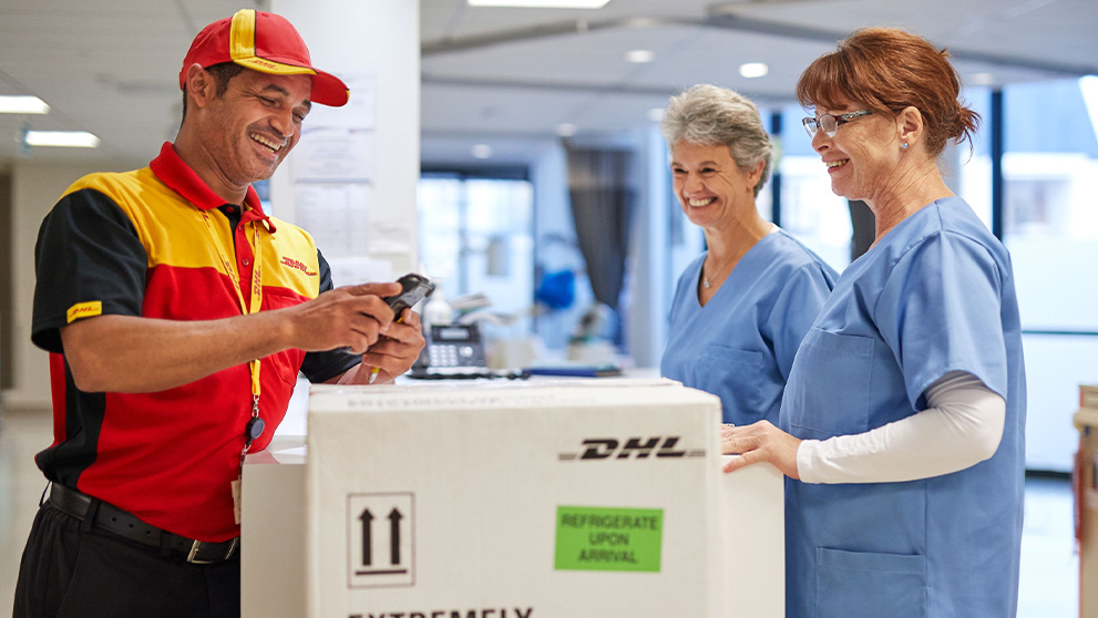 DHL courier scanning parcel with two medical professionals