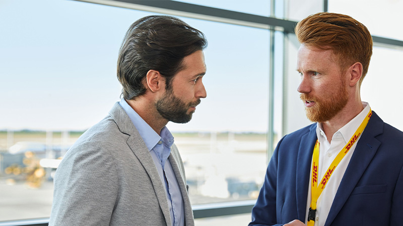 Two male DHL office workers having a discussion