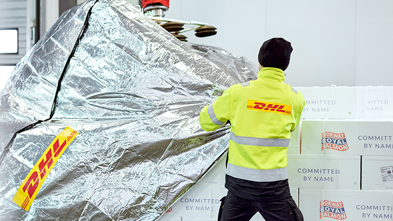 DHL employee wrapping white boxes in DHL branded foil
