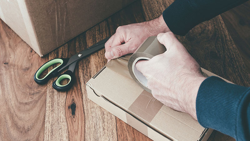 hand taping brown parcel
