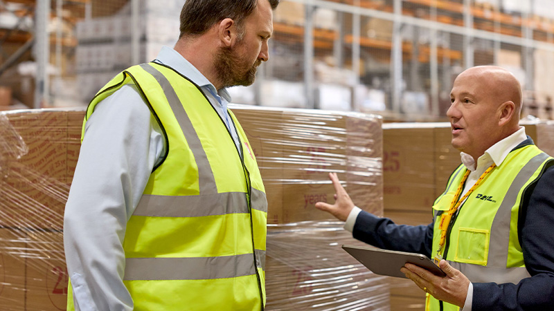 Two men in hi vis looking at large pallets