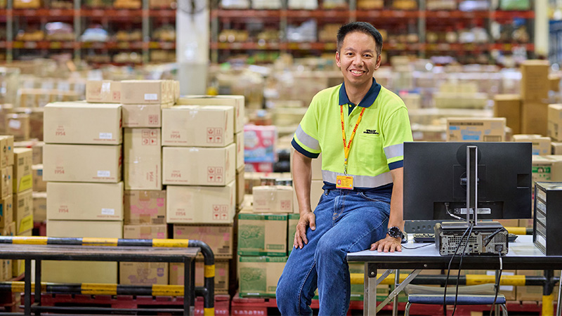 DHL employee sitting on a desk in a warehouse