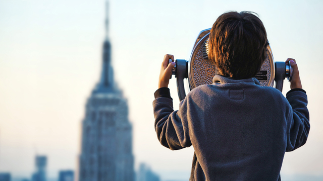 Boy looking at a cityscape through a telescope