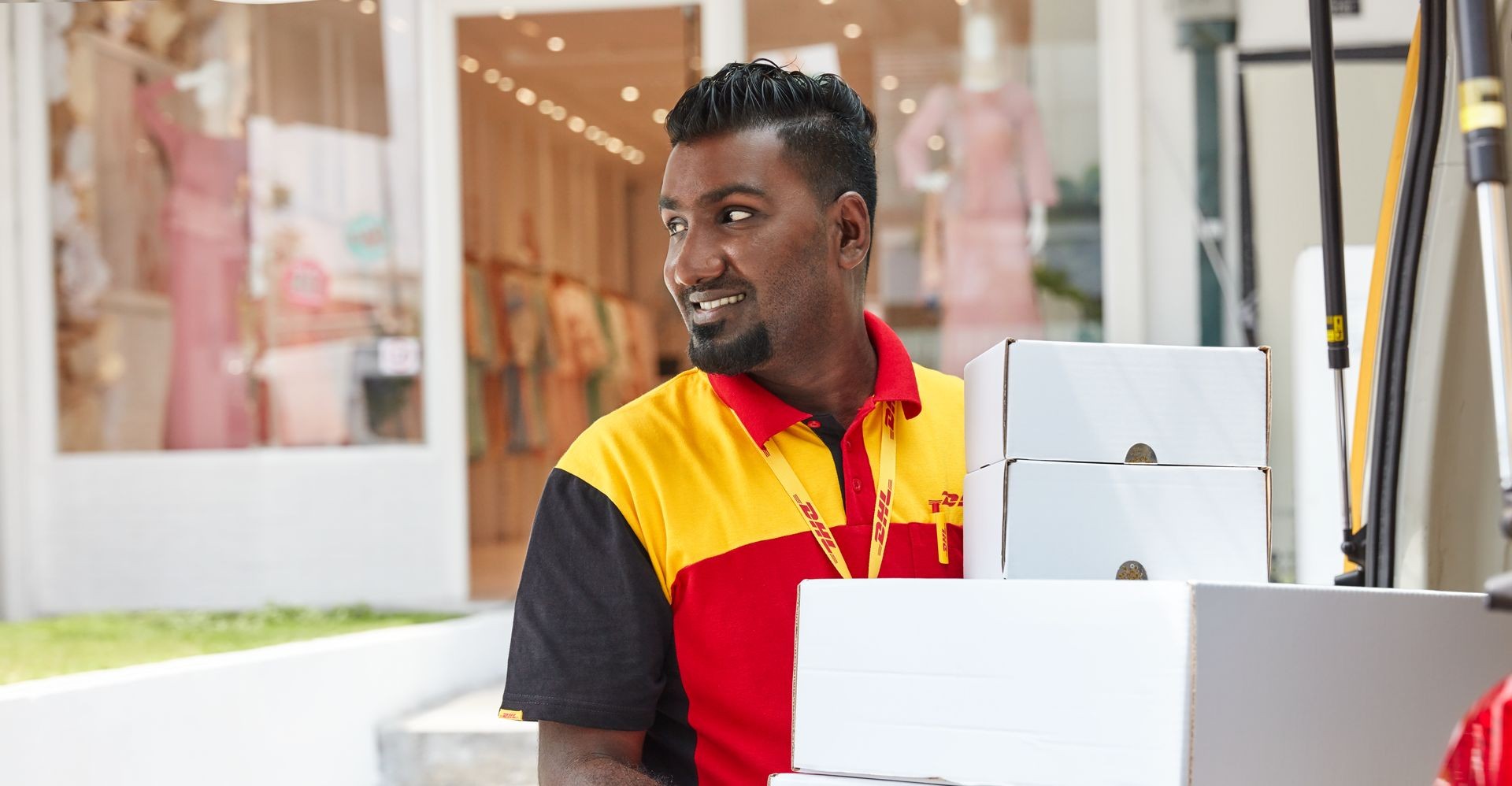 DHL employee carrying a stack of parcels.