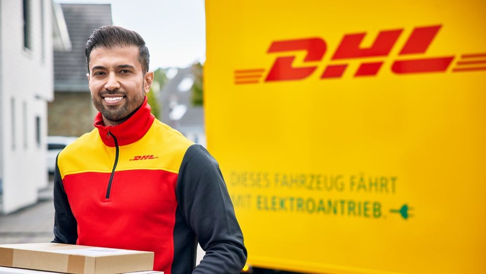 A DHL employee delivering a parcel, with a DHL van in the background.