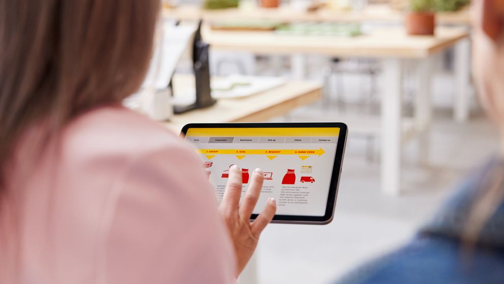 Seseorang yang memeriksa solusi pengiriman DHL di tablet selama konsultasi