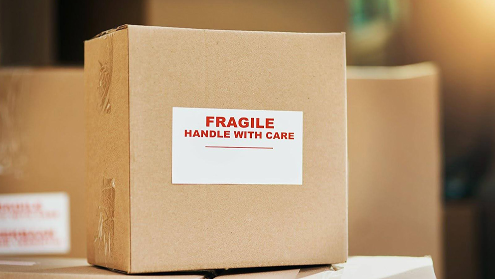 Barang rapuh di dalam kotak tahan lama yang ditandai dengan stiker rapuh