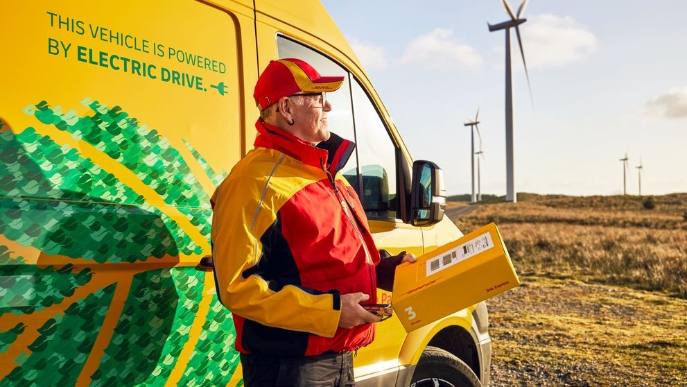 DHLの宅配員が電気自動車のそばに立っている