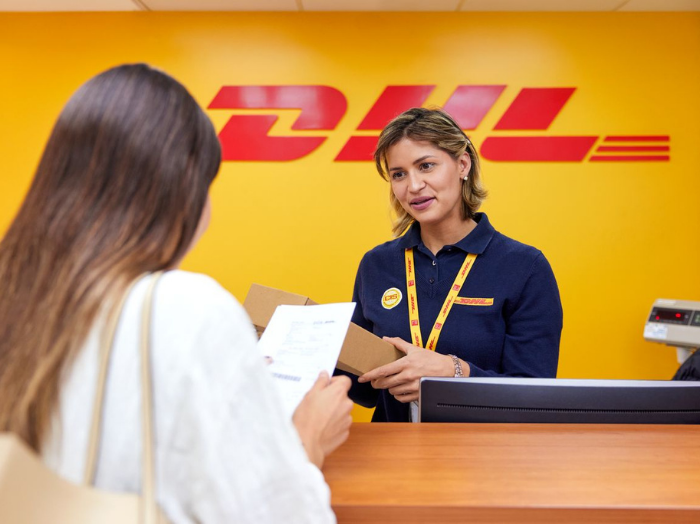 A DHL Express staff member assisting a female customer at a service point.