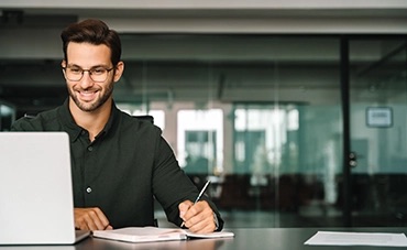 Hombre con gafas mirando la pantalla del portátil