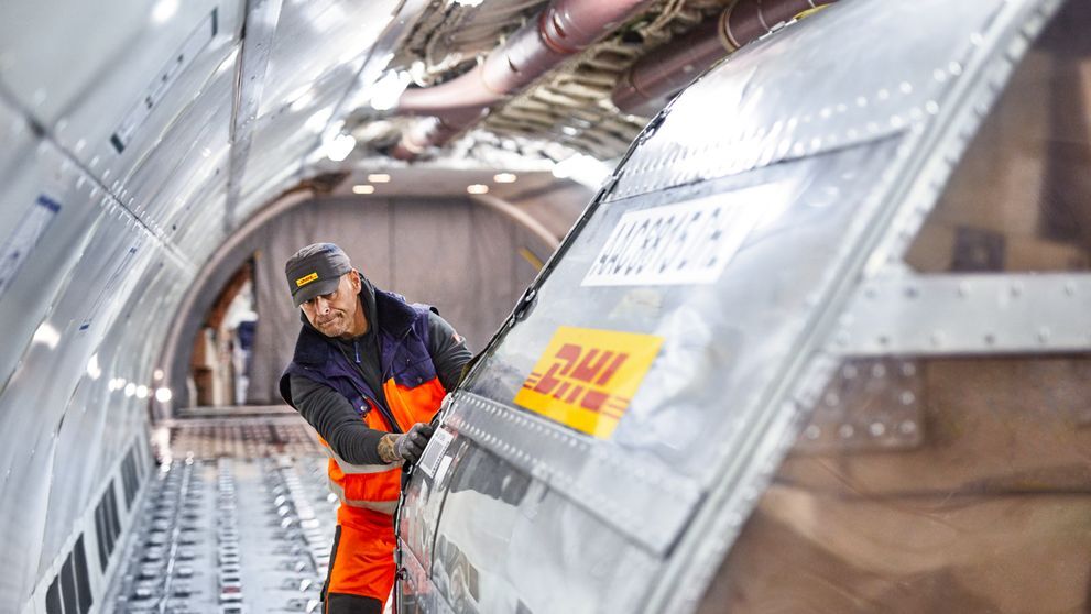 dhl express employee pushing air freight box for shipping heavy items