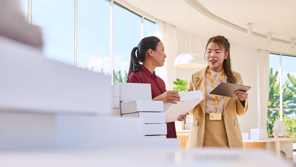 a dhl expert talking to a business owner while suggesting shipping solutions on her tablet