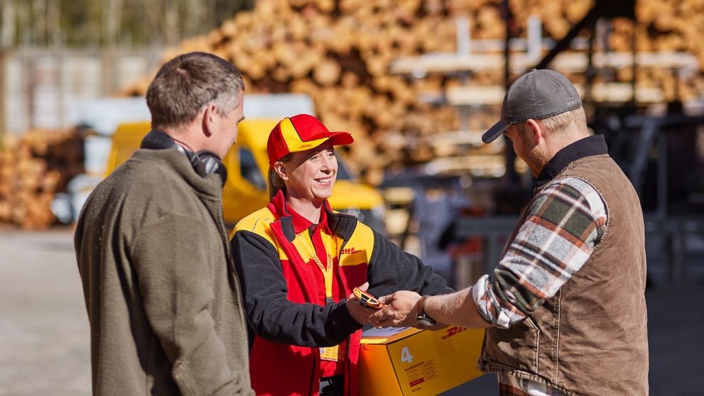 Female DHL employee interacting with two male New Zealand business owners