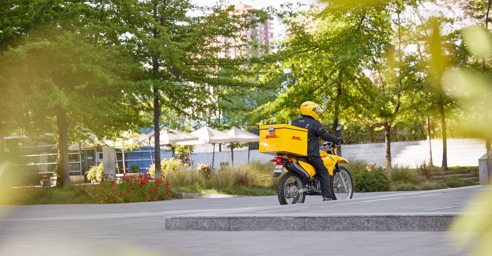 DHL express employee delivering a parcel in Pakistan while riding a motorcycle