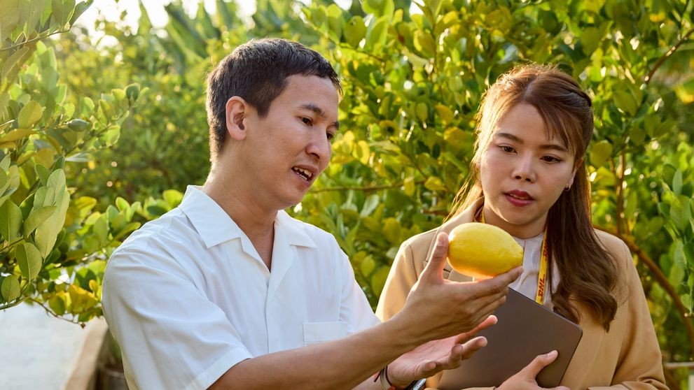 a filipino business owner showing a dhl employee his farm goods for export from the philippines