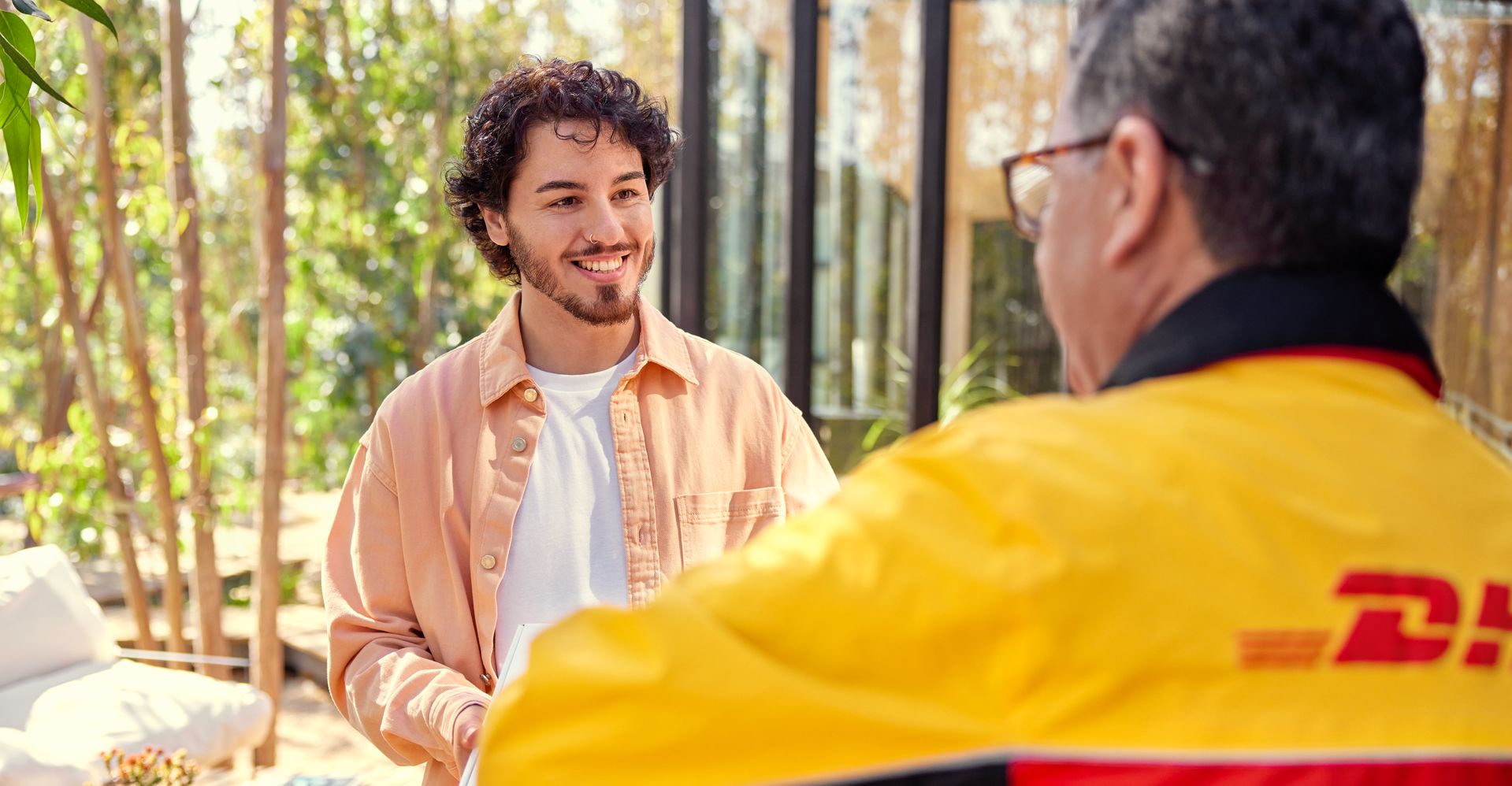 A man receiving a package from a DHL employee.