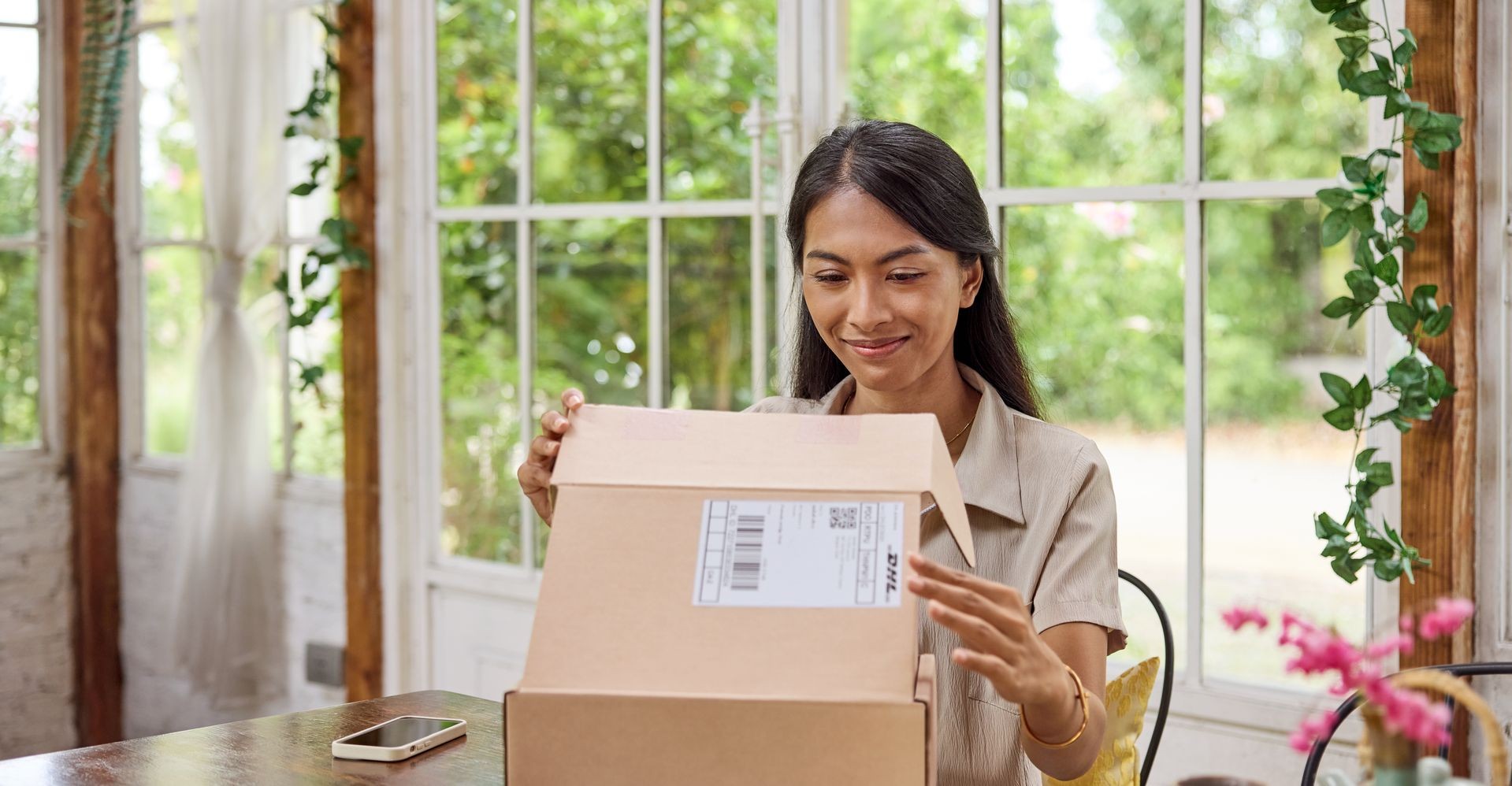 lady opening a parcel wrapped with dhl gogreen eco-friendly packaging