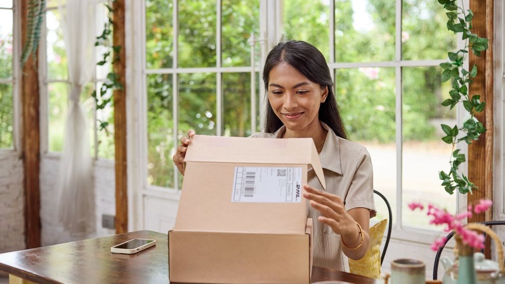 lady opening a parcel wrapped with dhl gogreen eco-friendly packaging
