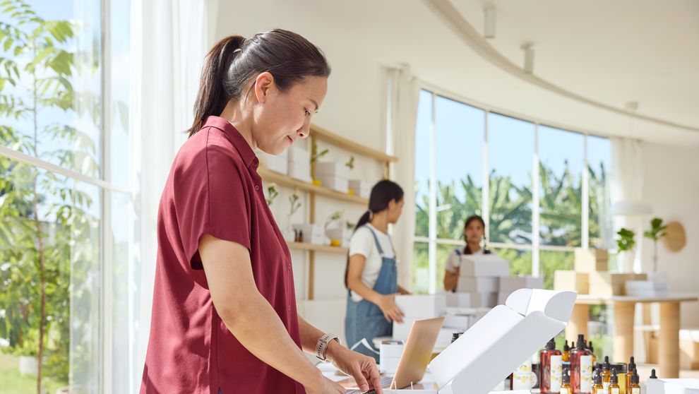  A middle-aged female shop owner is packing an online order for shipping