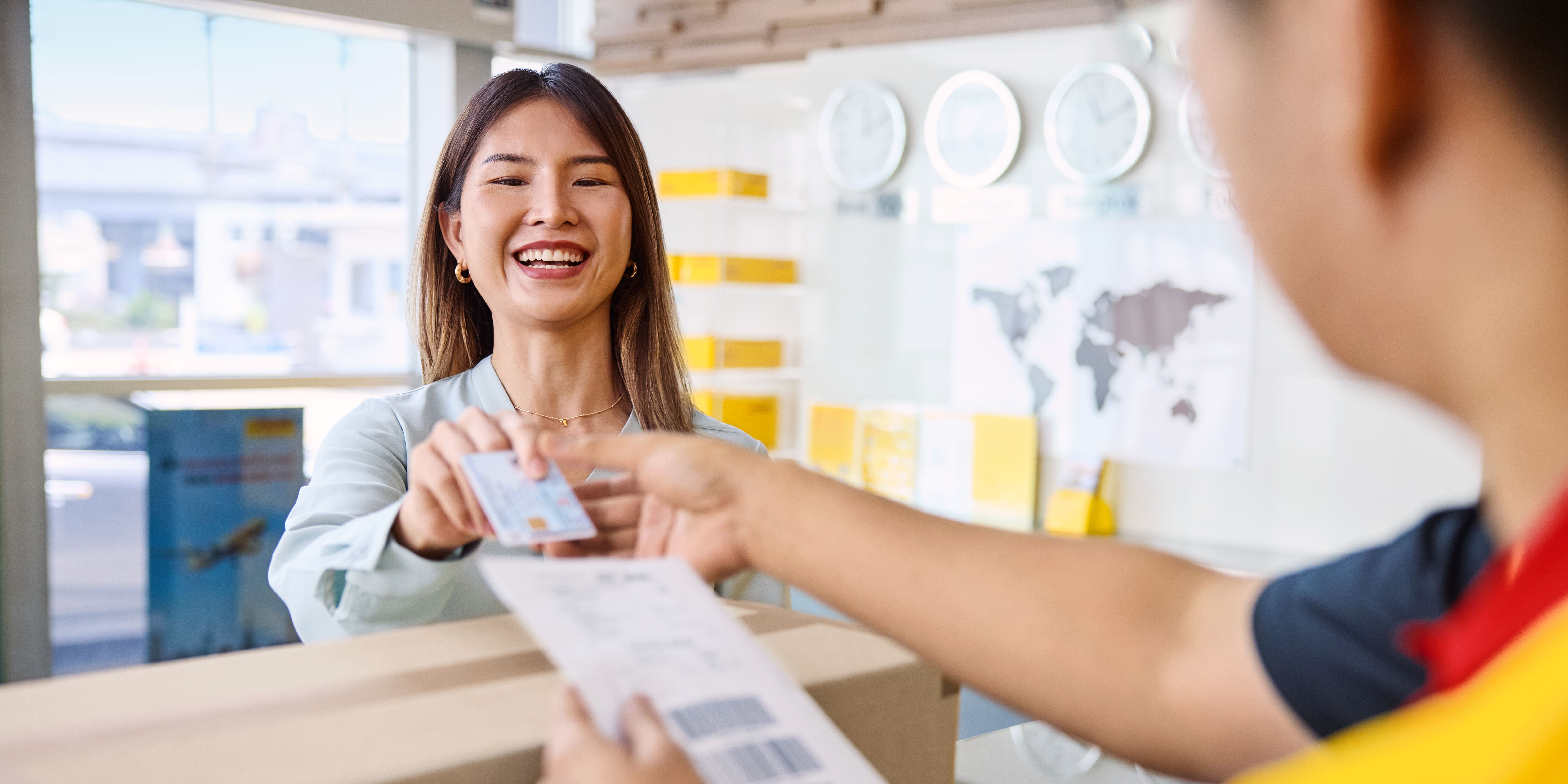 DHL customer handing over her parcel at a DHL service point