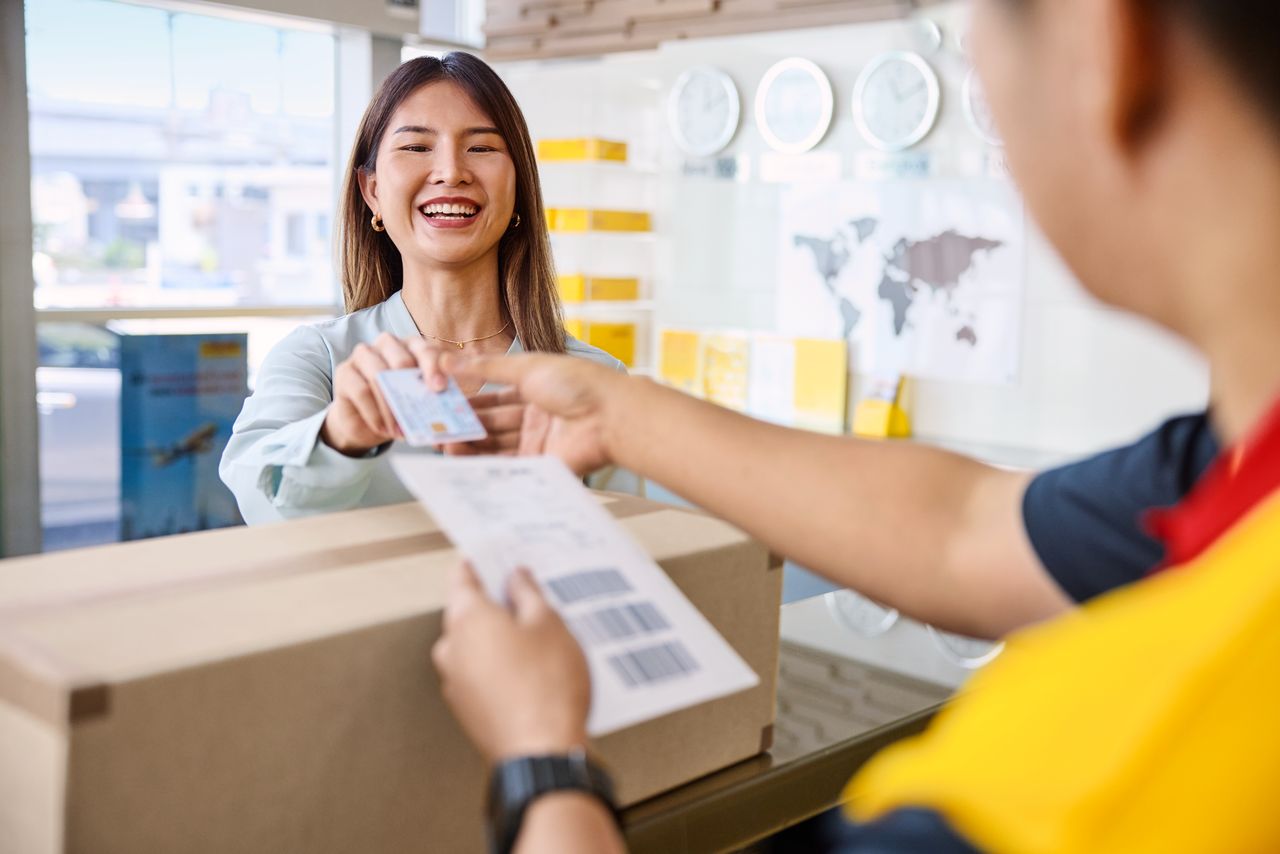 DHL customer handing over her parcel at a DHL service point