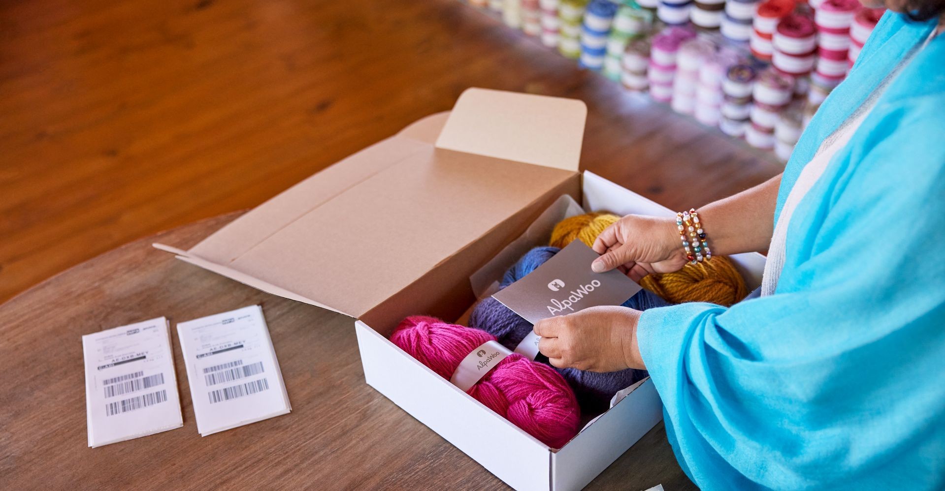  A person carefully packing colorful yarn into a shipping box for international delivery.