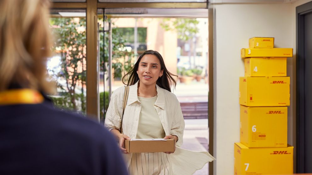 a female customer enters dhl service point with a return parcel