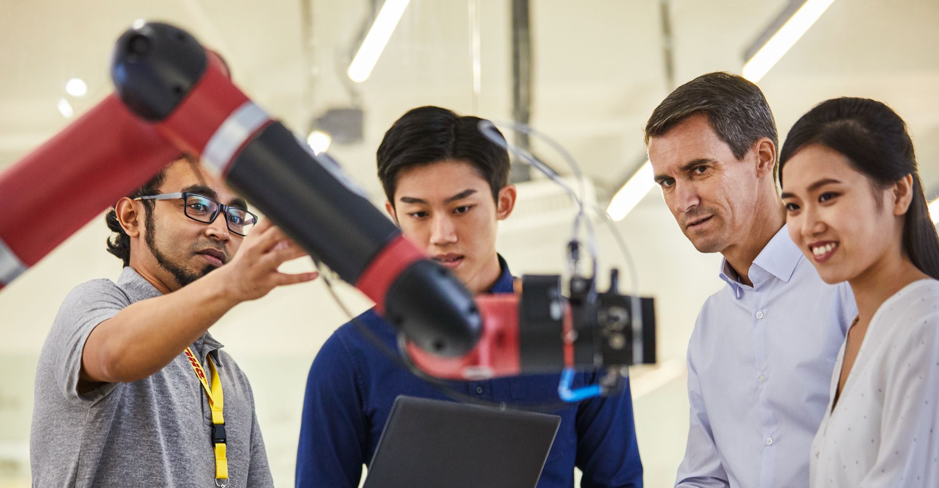 A DHL employee explaining robotics technology to a group of colleagues, showcasing the integration of AI and robotics in logistics operations