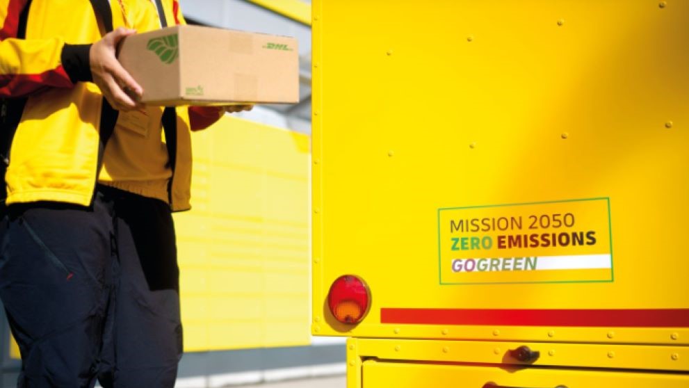 dhl express employee holding a sustainable package next to a gogreen vehicle