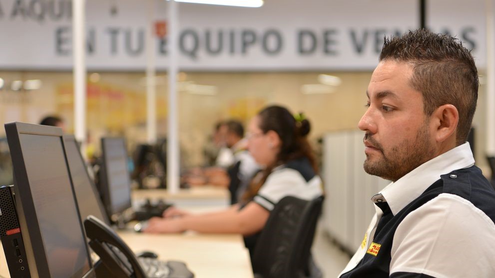 DHL staff managing international shipments with computer software