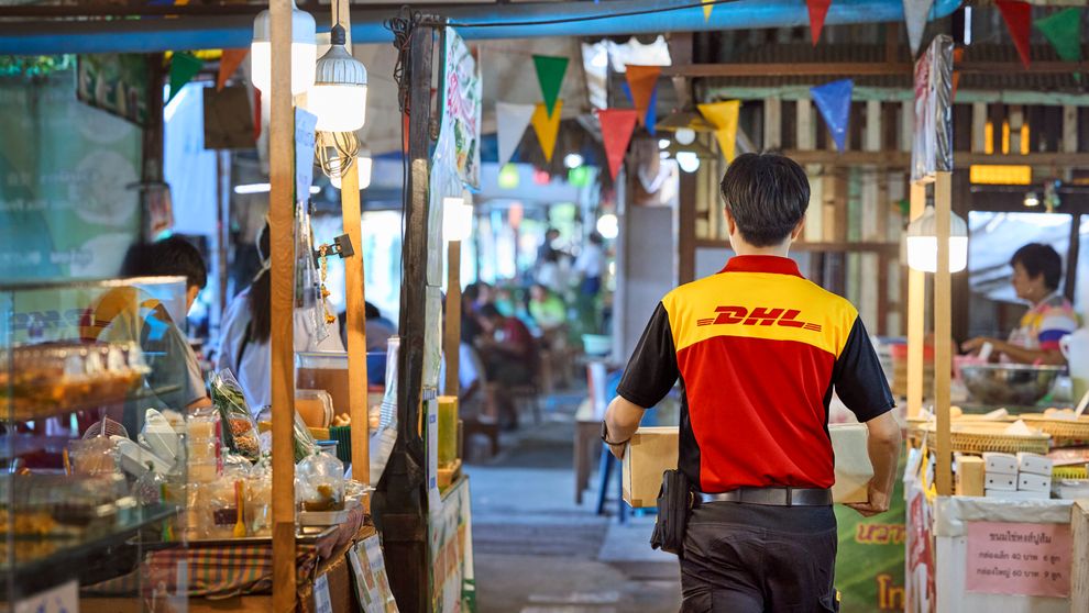 DHL courier delivering parcel in thai street market