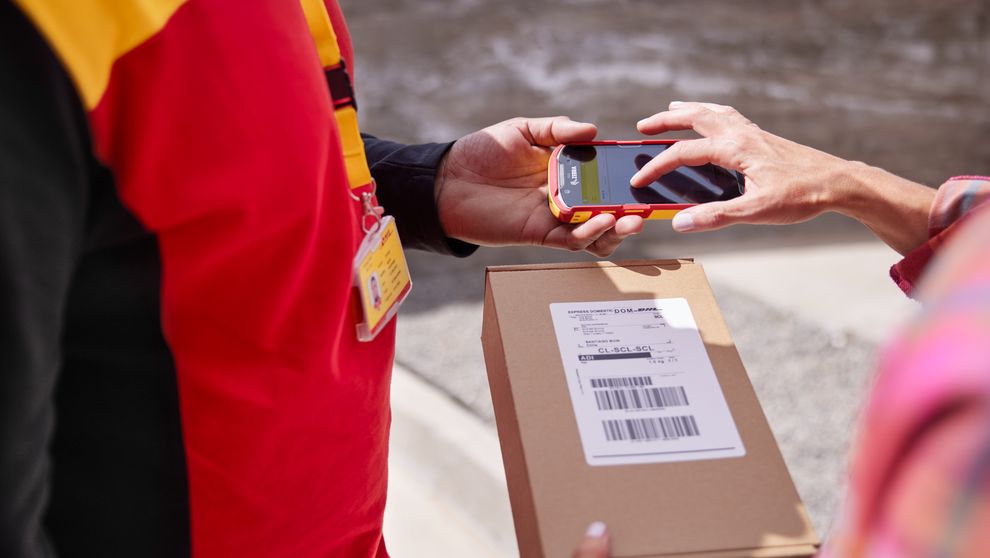 close-up of DHL Express employee handling the DHL GoGreen packaging box from a customer