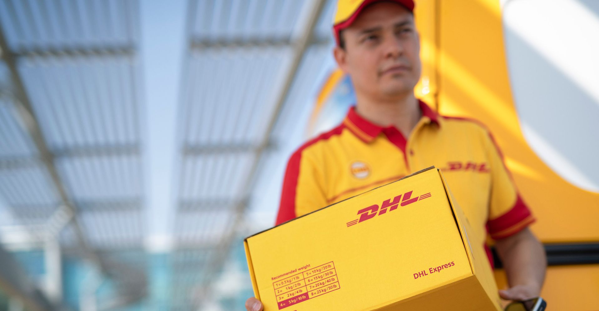 DHL Express Courier ถือพัสดุสําหรับการจัดส่งอีคอมเมิร์ซระหว่างประเทศ