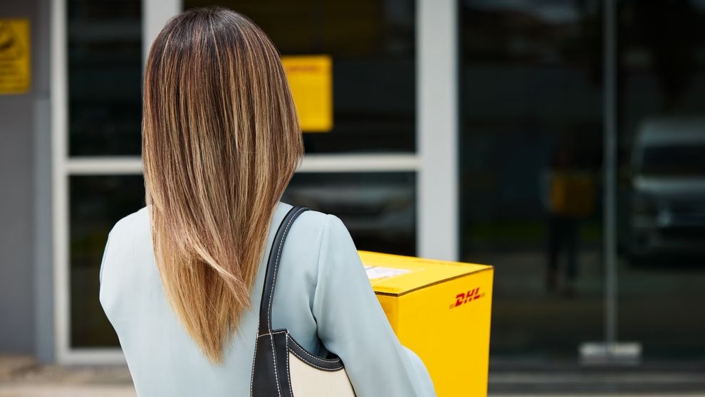 ลูกค้าหญิงคนหนึ่งกําลังเดินทางไปส่งพัสดุ DHL Express ที่ DHL ServicePoint